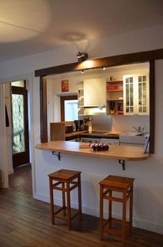 a kitchen with two stools in front of the counter