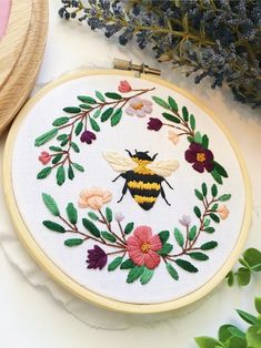 a close up of a embroidery on a table with flowers and a bee in the middle