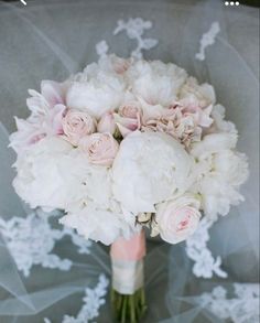 a bridal bouquet with white and pink flowers on a gray clothed chair cover