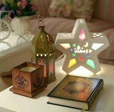 a table topped with an open book next to a lit candle and a star shaped lantern