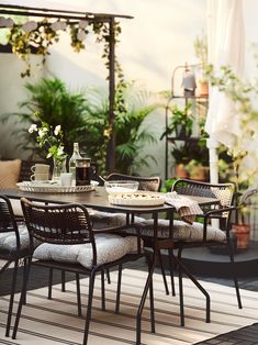 an outdoor table and chairs on a wooden deck with potted plants in the background