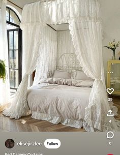 a white canopy bed sitting in a bedroom next to a window with curtains on it