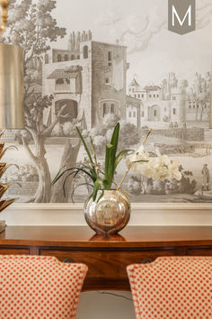 two vases with flowers sit on a table in front of a wallpapered background