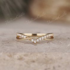 a yellow gold wedding band with three small diamonds in the middle, set on top of a stone surface