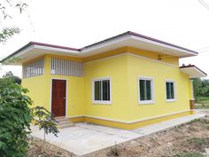 a small yellow house sitting on top of a dirt field