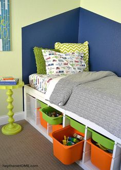 a bed with storage bins underneath it in a room that is painted blue and green