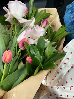 pink and white flowers are in a vase on a table with polka dot napkins