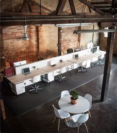 an overhead view of a room with desks and chairs, exposed brick walls, and concrete floors