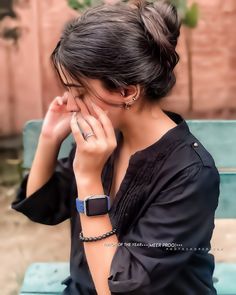 a woman sitting on top of a blue bench holding her hand to her face and covering her eyes