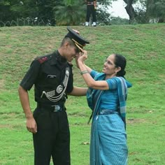 a man and woman in uniform standing next to each other on a lush green field