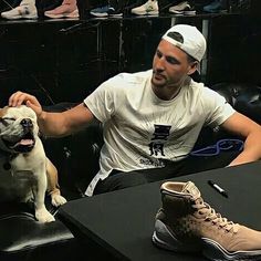 a man sitting at a table with a dog in front of him and shoes on the floor