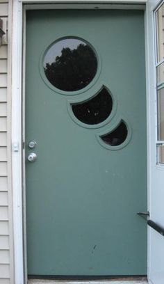 a green door with three round windows on it