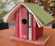 a birdhouse made out of books sitting on top of a table