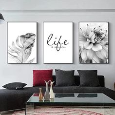 three black and white paintings on the wall above a couch in a living room with red pillows