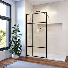 a bathroom with a large window and a shower in the corner next to a potted plant