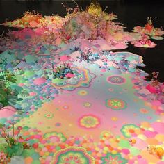 an art installation is shown with many different colors and patterns on the ground, as well as flowers