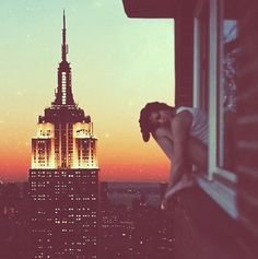 a woman leaning against a window looking out at the empire building