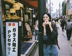 a woman standing on the sidewalk eating food