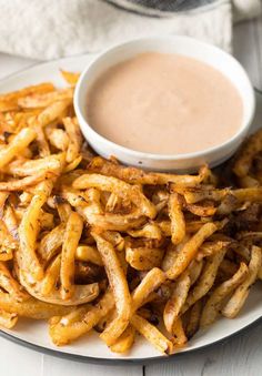 there is a plate with french fries on it and a bowl of dipping sauce in the background