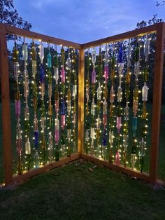 a fence made out of wine bottles with lights on it and some trees in the background