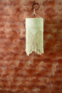 a white crocheted dream catcher hanging from a hook on a wall with a brown background