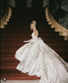 a woman in a white dress standing on some stairs