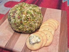 a wooden cutting board topped with crackers and a cheese ball