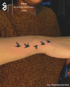 a woman's arm with birds flying in the air on her left arm, which is