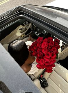 a man sitting in the back seat of a car holding a bouquet of red roses