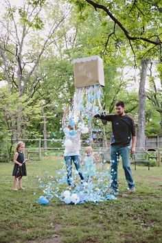 a man and girl are throwing confetti at each other in the park while another child looks on