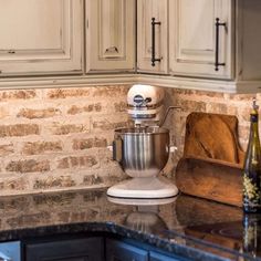 a kitchen counter with a mixer on top of it next to a bottle of wine