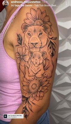 a woman's arm with a lion and flowers on the back of her shoulder