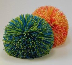 two balls of yarn sitting next to each other on a white surface with one colorful ball in the middle