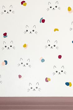 the wall has many cats on it and is painted with different colors, shapes and sizes