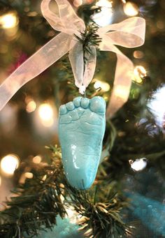 an ornament hanging from a christmas tree with the foot of a baby's feet