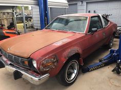 an old rusted car is being worked on by a man with a jack wrench