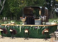 an outdoor bar decorated with fake flowers and cowboy hats for the guests to sit at