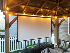 an outdoor movie screen is set up on the back porch with chairs and tables under it