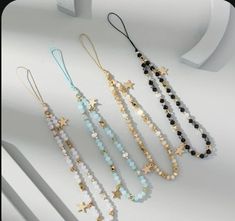 five different necklaces with stars and beads on each one side, all lined up against a white background