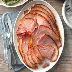 slices of ham on a plate next to silverware