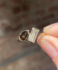 a person holding a ring with a brown stone in it