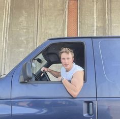 a man sitting in the driver's seat of a blue truck