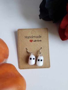 two small white earrings with black eyes on them