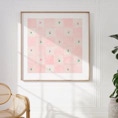 a pink and green painting hanging on the wall next to a wicker chair in a white room