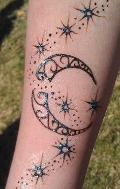 a person with a tattoo on their arm that has stars and the moon painted on it