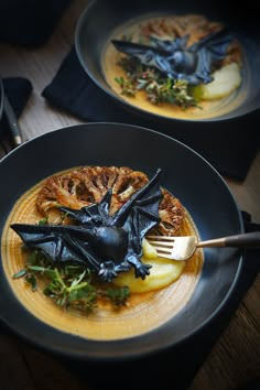 two black plates with food on them, one has a bat shaped piece of meat