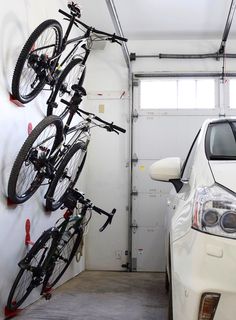 two bikes are hanging on the wall next to a car