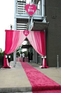 the entrance to an event decorated with pink and white drapes