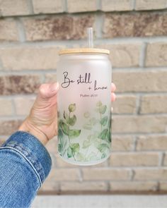 a person holding up a glass with the words be still and have written on it