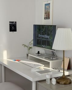 a white desk with a computer on it and a lamp in front of the monitor